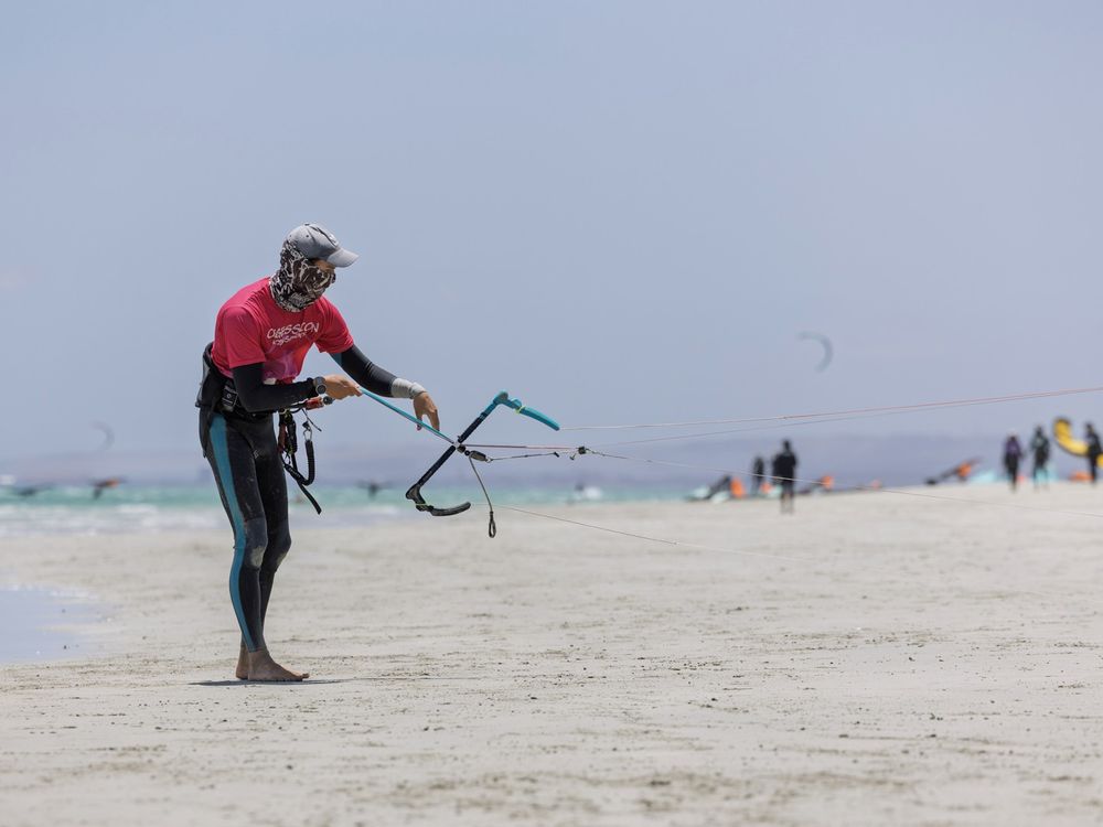 An instructor demonstrating the control bar on the beach, lines laid out