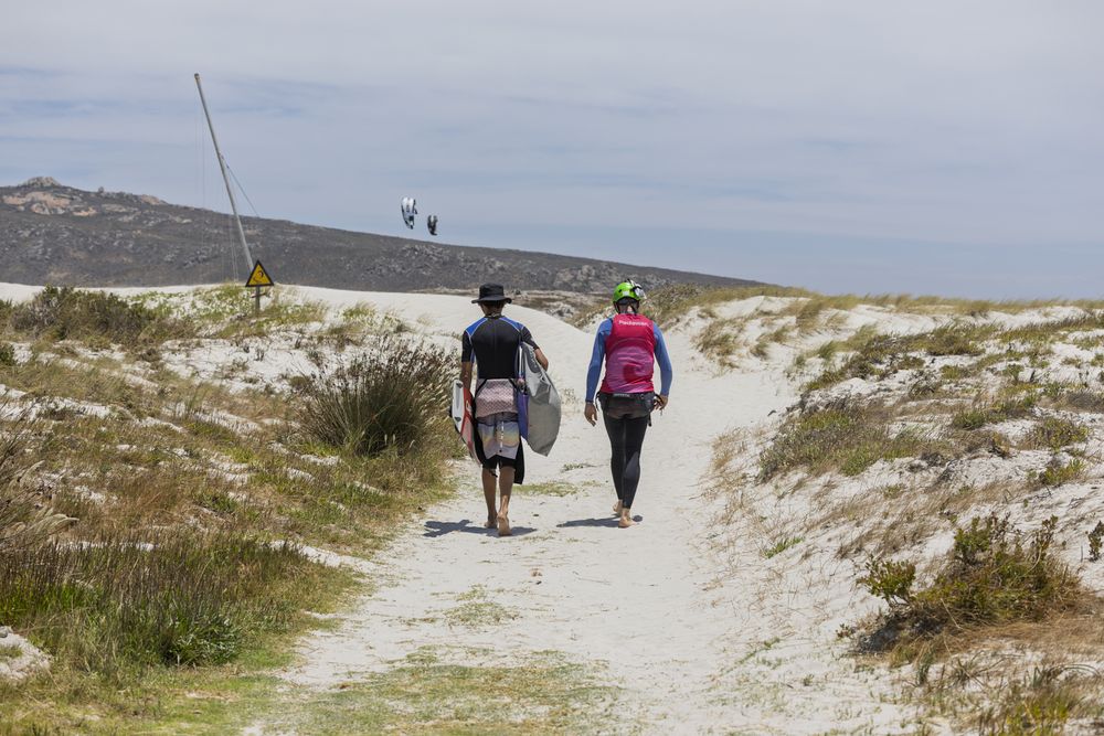 Two riders walking the sandy path over the dunes to the water