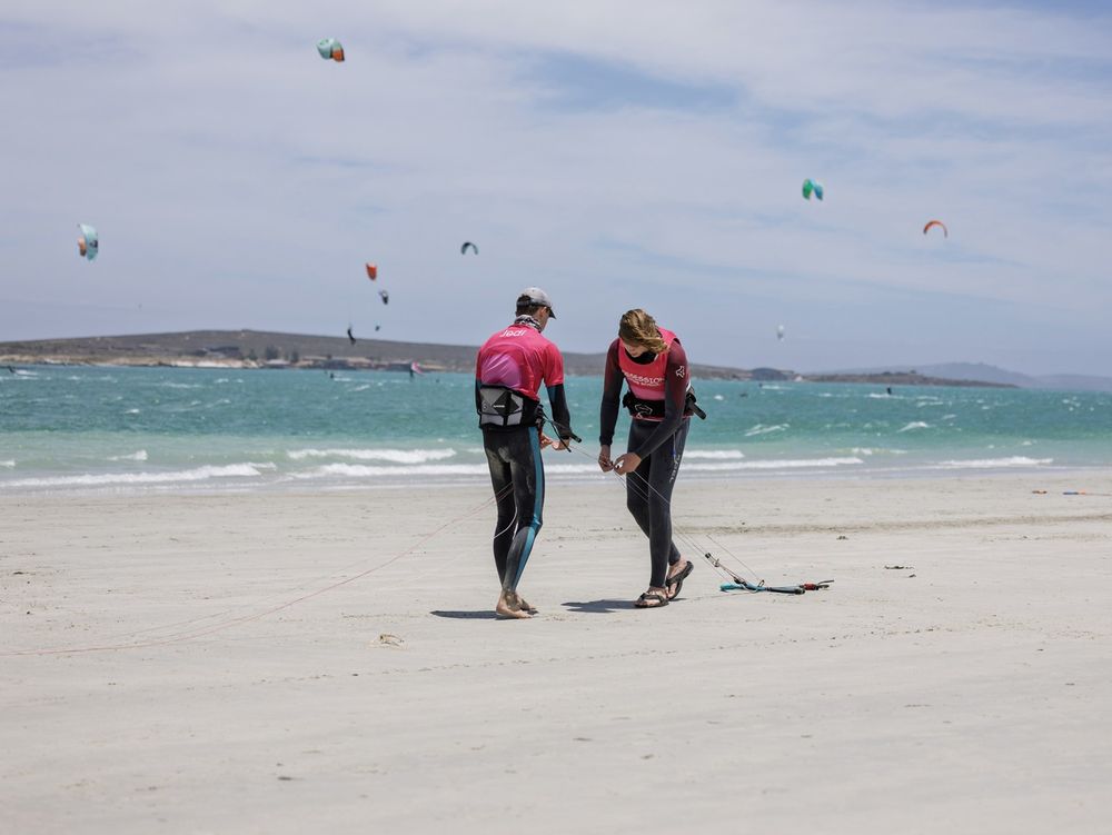 Two riders walking a wide, near-empty stretch of Langebaan beach