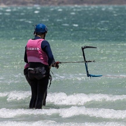A rider standing in the shallows holding a foil board