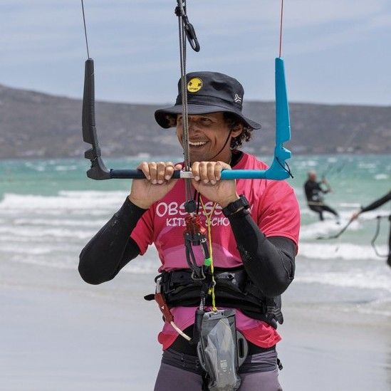An Obsession Kiting instructor holding a wing by the boom on the beach