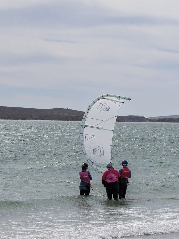Two students in the water with a kite parked overhead