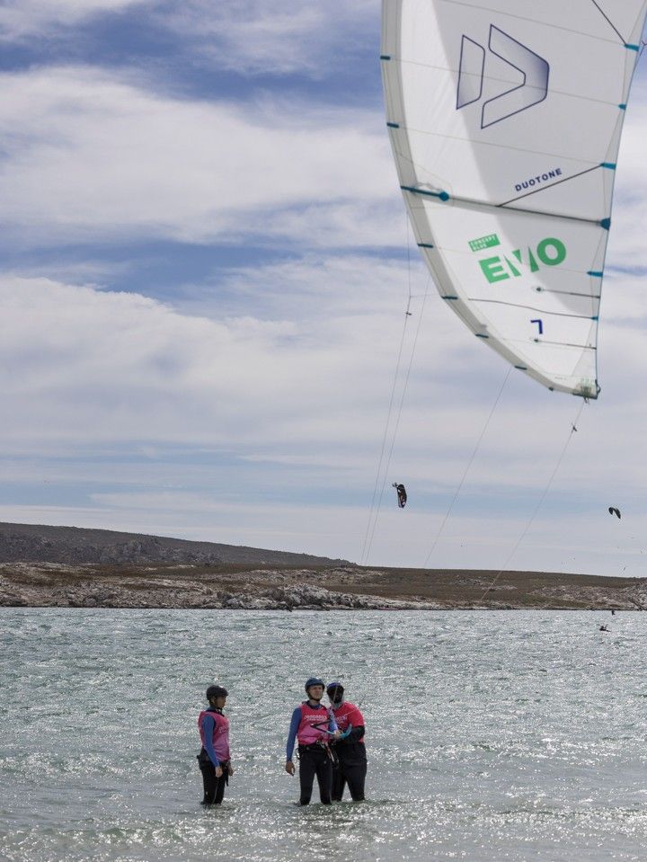 A kite flying above two students standing together in the shallows