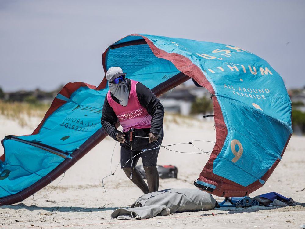 An Obsession Kiting instructor holding a kite up on the sand before a lesson