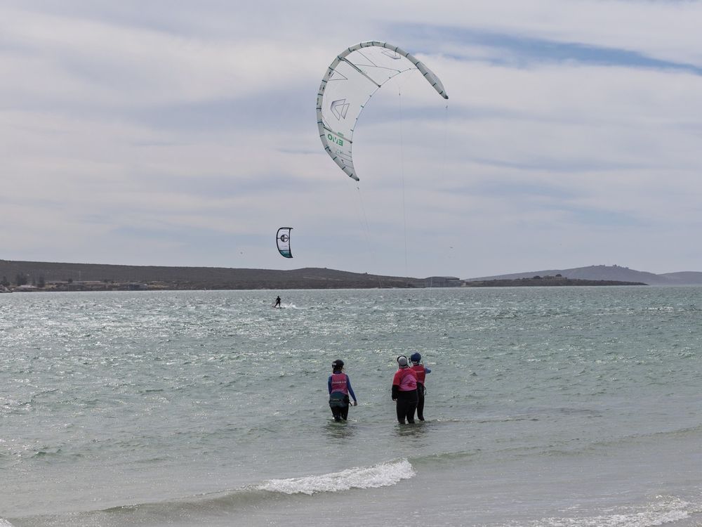 A student and instructor standing in the shallows with a training kite overhead