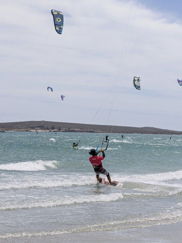 A kitesurfer riding close to shore with kites out on the lagoon behind