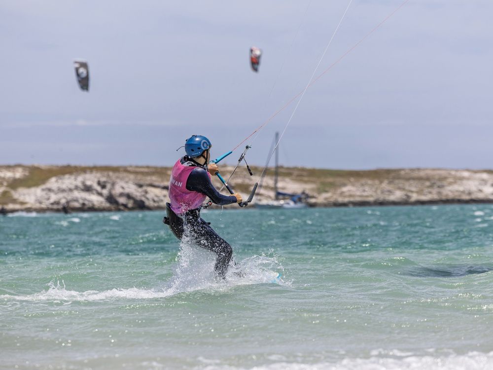 A kitesurfer carving a turn with the kite overhead and the lagoon behind