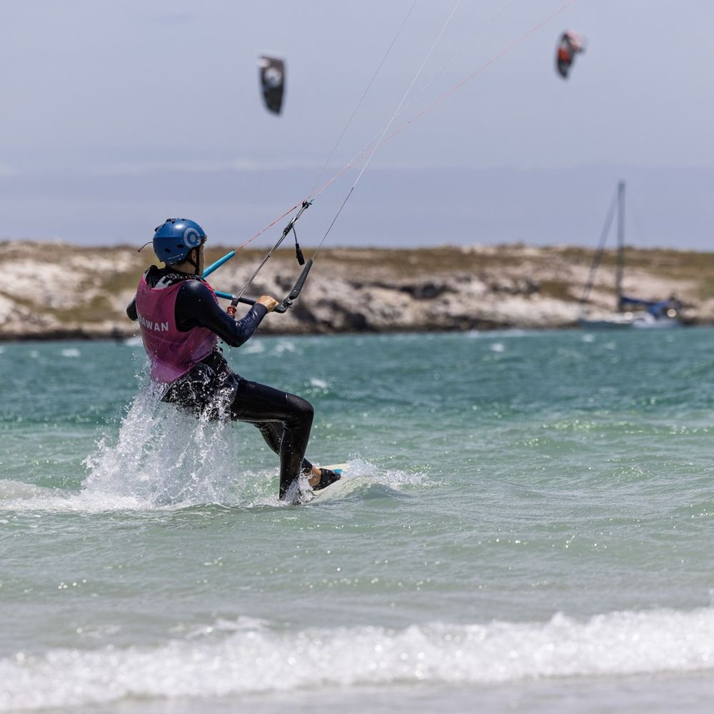 A kitesurfer riding through the chop with spray off the board