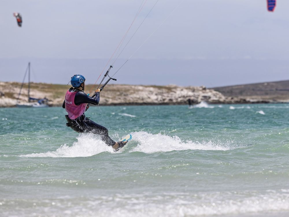 A kitesurfer riding upwind with the kite high above