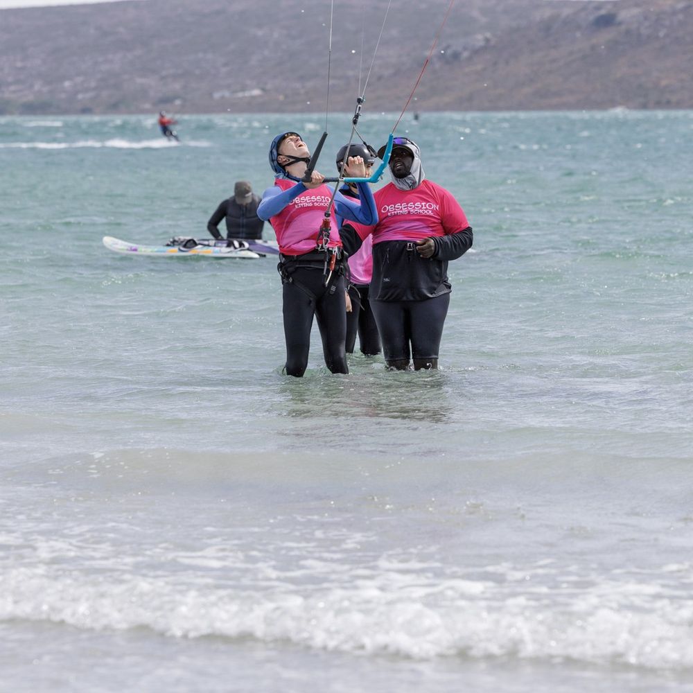 An instructor with two students and a board in the shallows