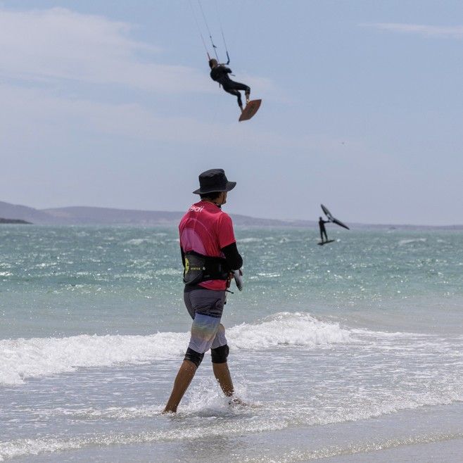 A kitesurfer jumping on the lagoon, seen from the water's edge