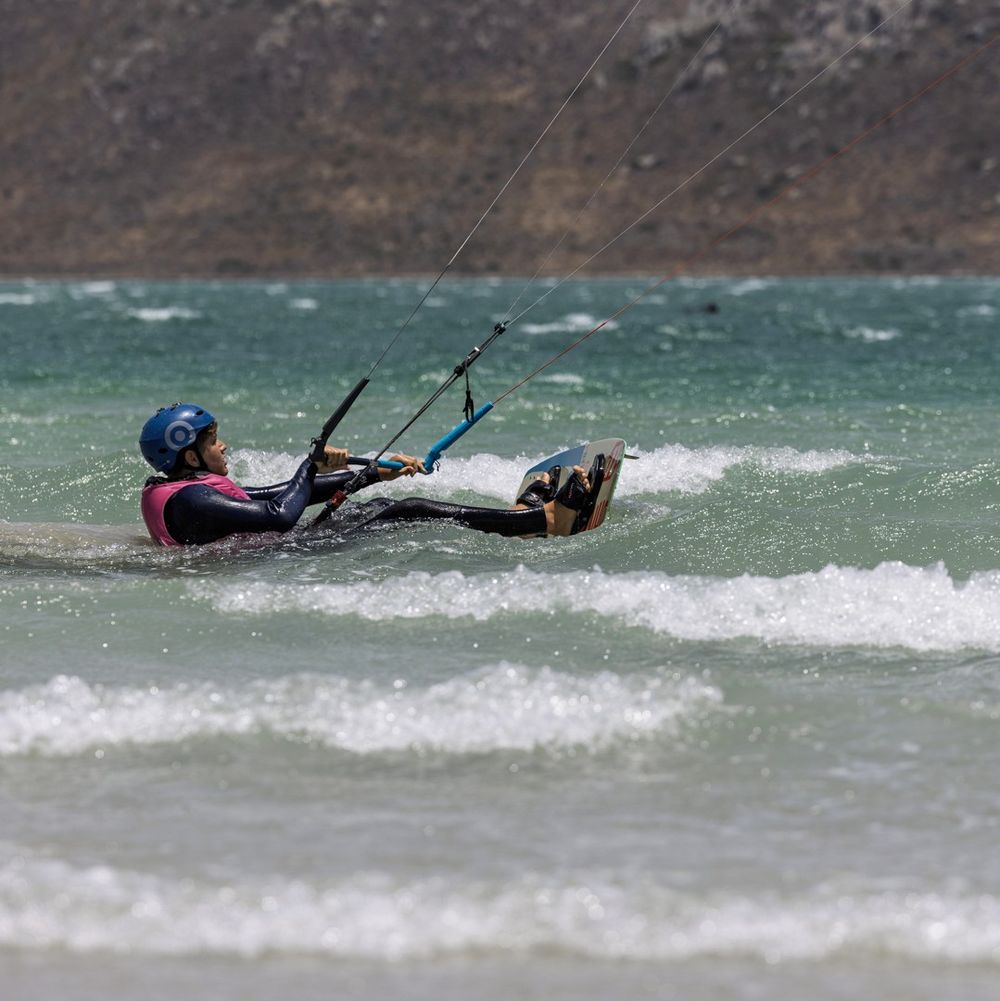 A kitesurfer getting up onto the board in the shallows