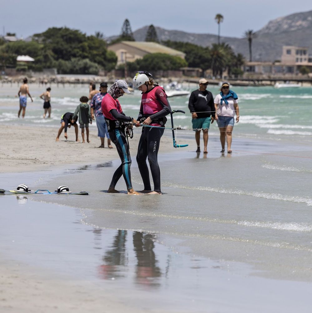 Riders at the water's edge with the town of Langebaan behind