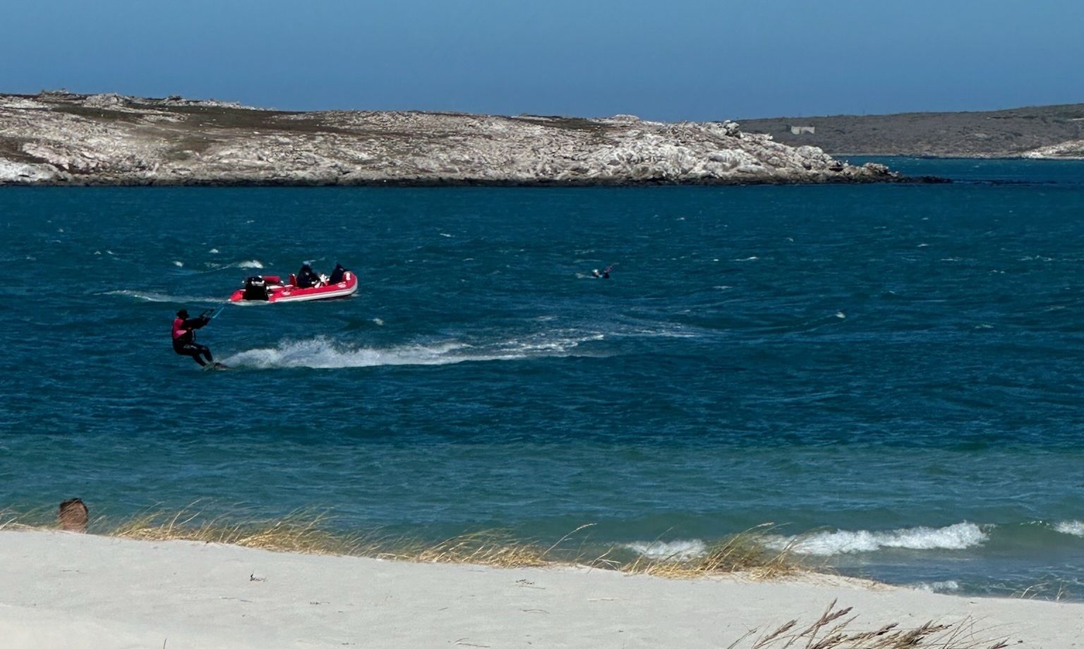 The Langebaan lagoon rescue boat shadowing a kitesurfer while a second rider is recovered from the water