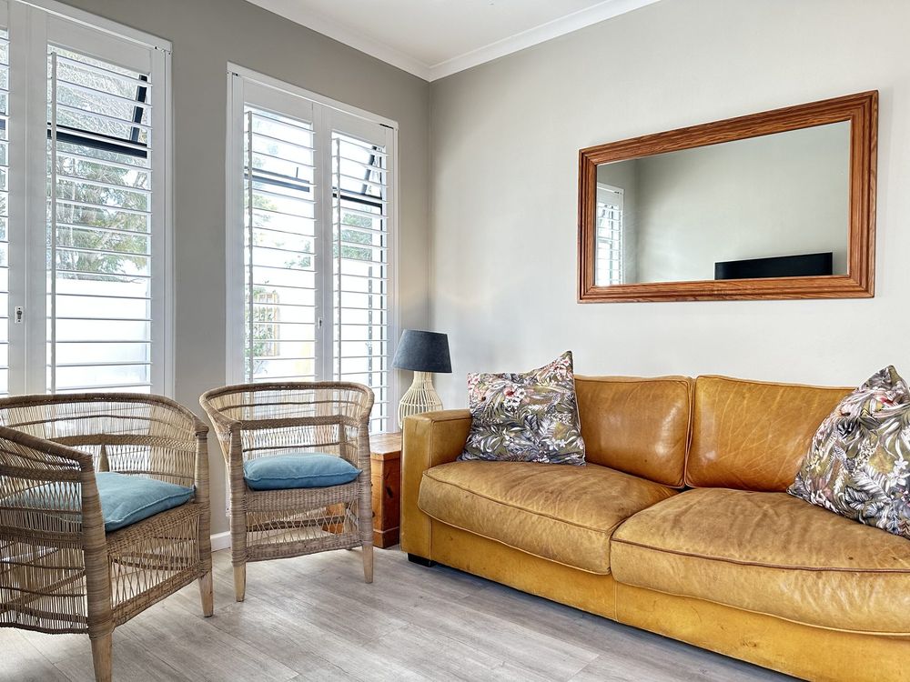 The living room at Kite Cottage, with a leather sofa and cane chairs