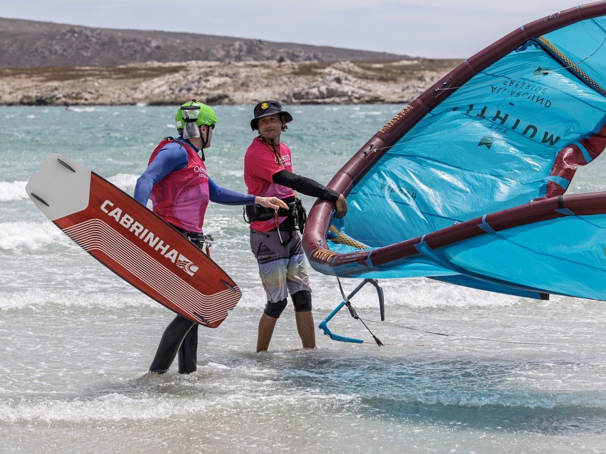 An Obsession Kiting instructor helping a student with a wing in the shallows at Langebaan